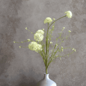 Delicate white flowers in a simple vase against a muted gray background.